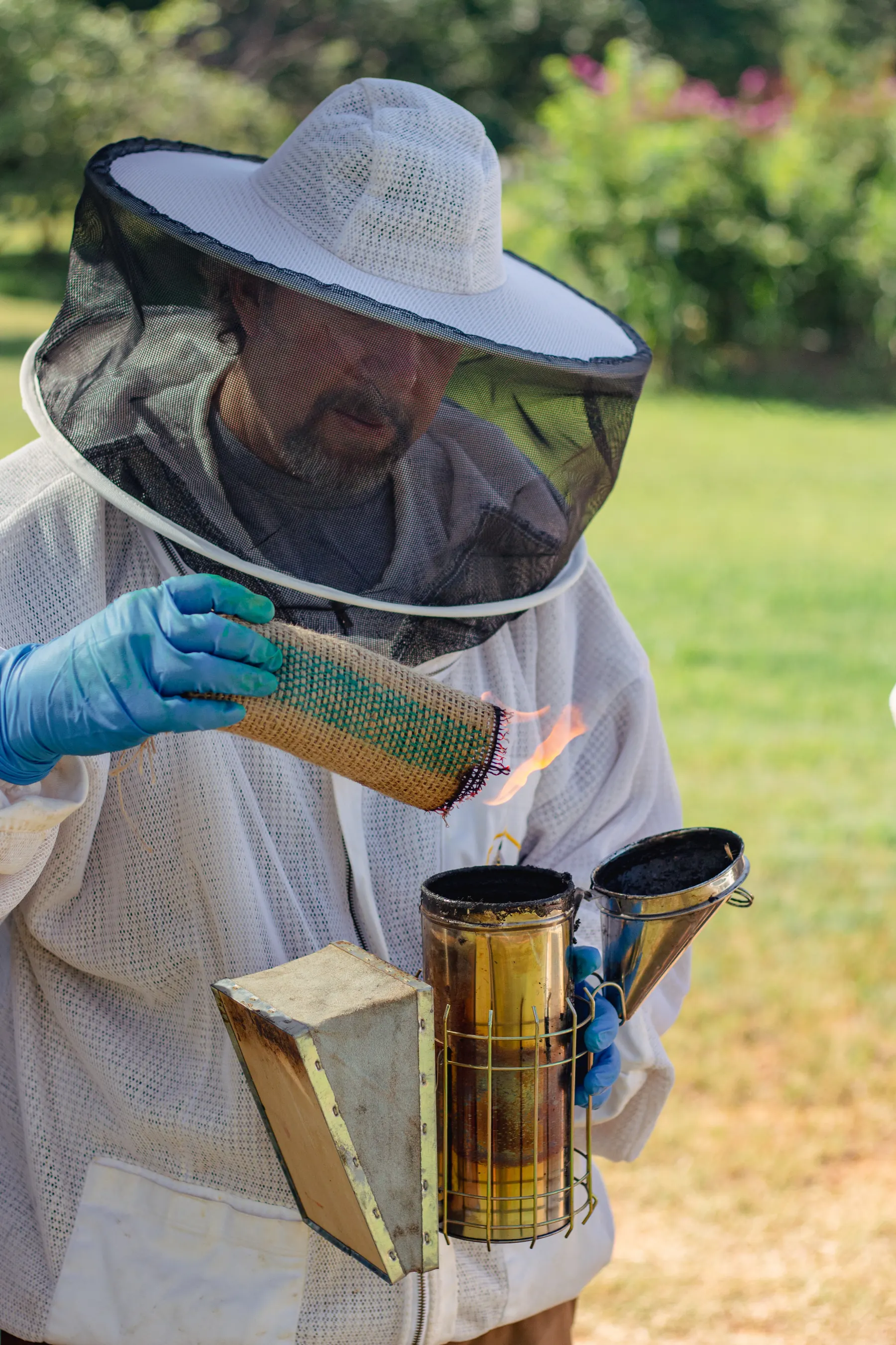 Jimmy Hughes lighting burlap fuel for a bee smoker before a hive visit.